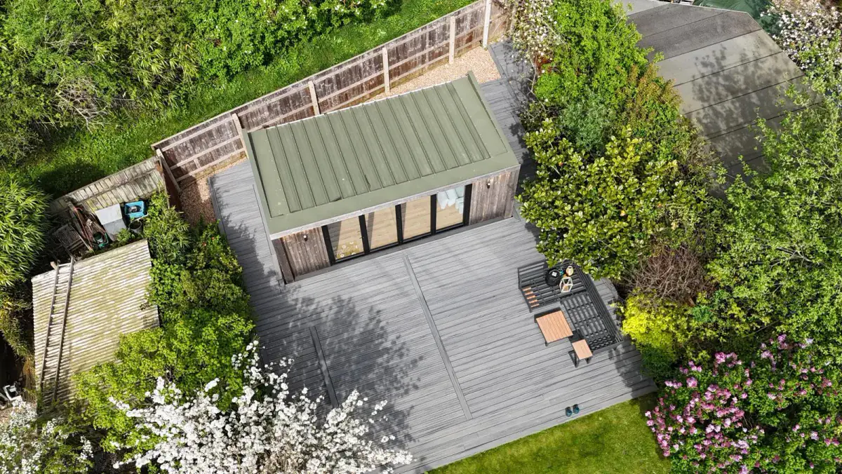 An aerial view of a garden room and deck surrounded by planting