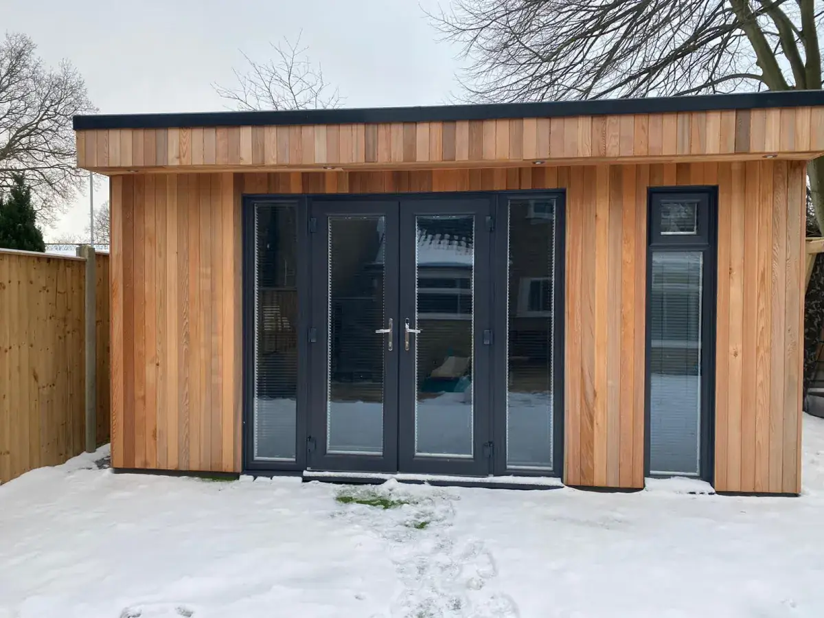 A cedar-clad garden room in the snow