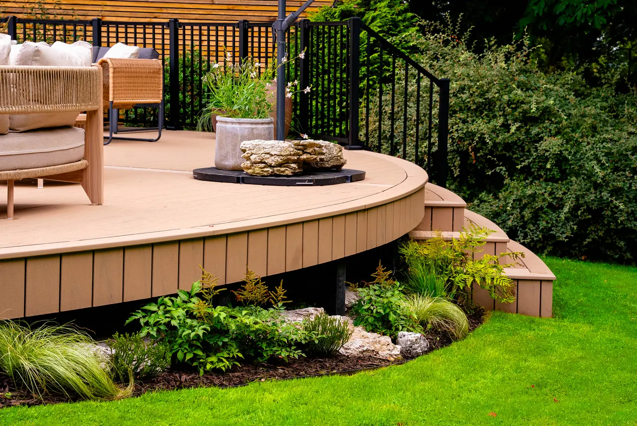 The curved edge and steps of a raised Trex Transcend Lineage deck in Carmel, black railing above
