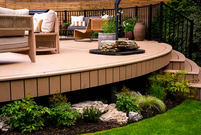 The curved edge of a raised Trex Transcend Lineage deck in Carmel, with stone and planting below