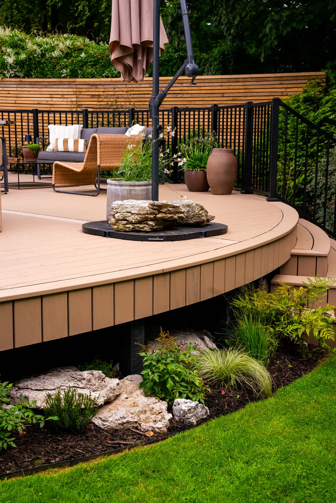 A curved, raised Trex Transcend Lineage deck in Carmel above a planted border