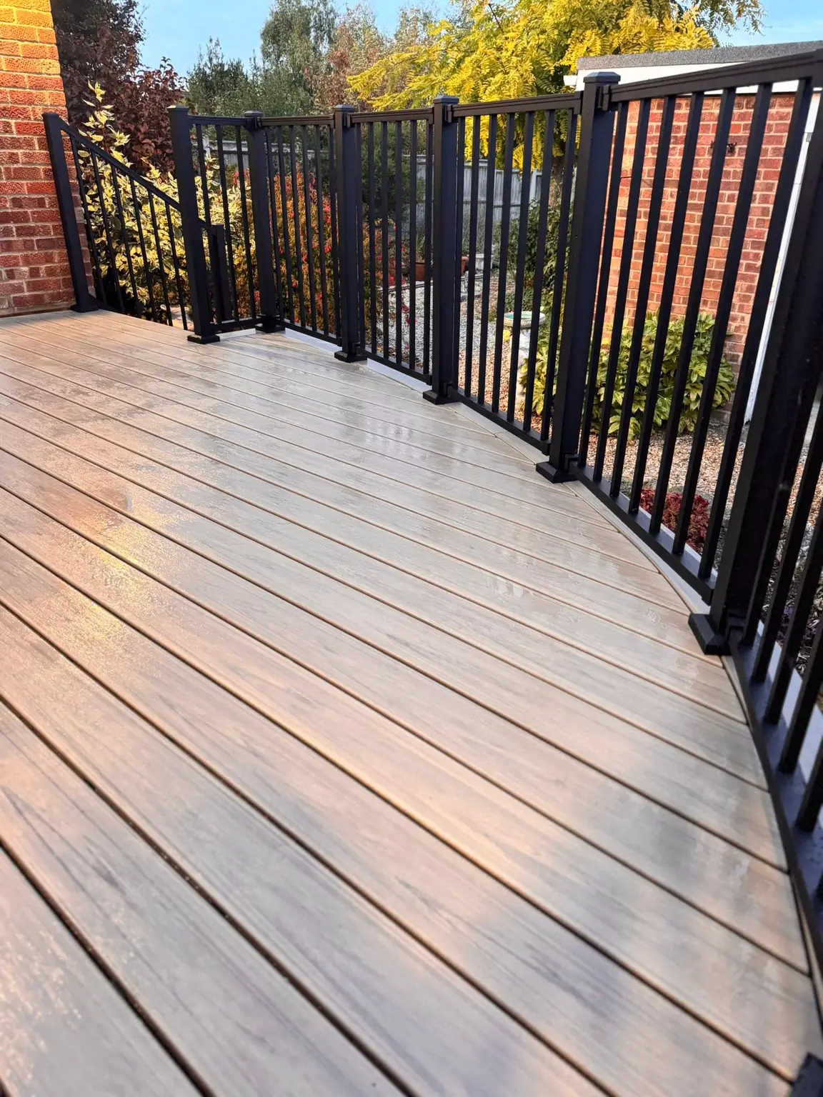 Black railing following the curved edge of a composite deck
