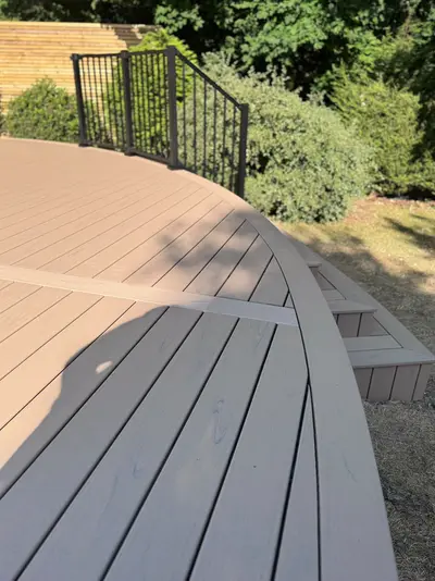 A curved Trex deck with a curved fascia board and black railing