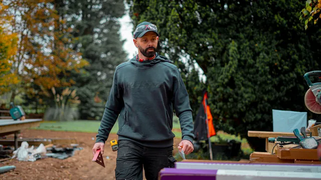Darren Gooch walking across a building site with tools in hand