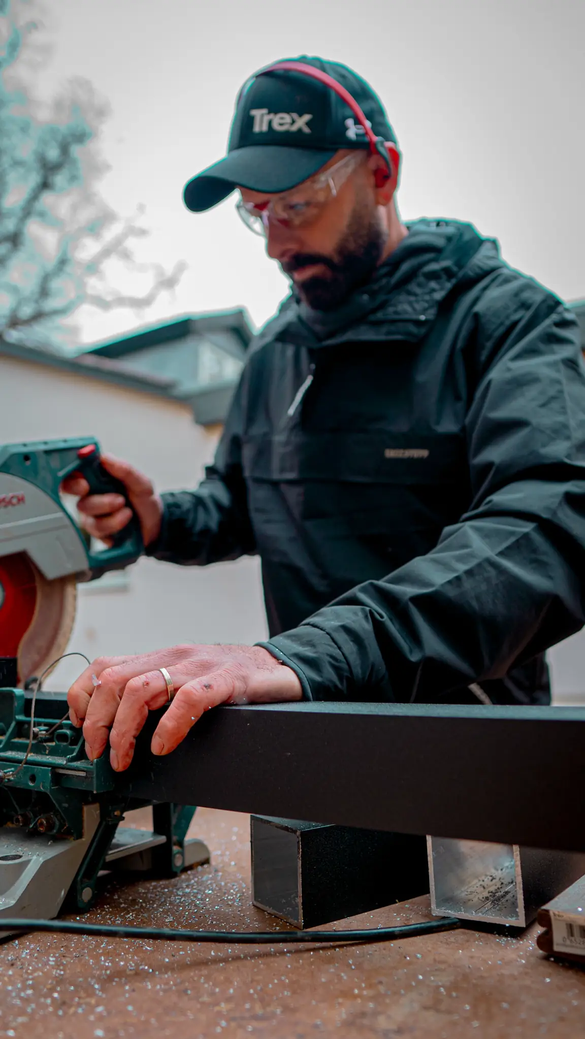 Darren in a Trex cap cutting a board on a mitre saw