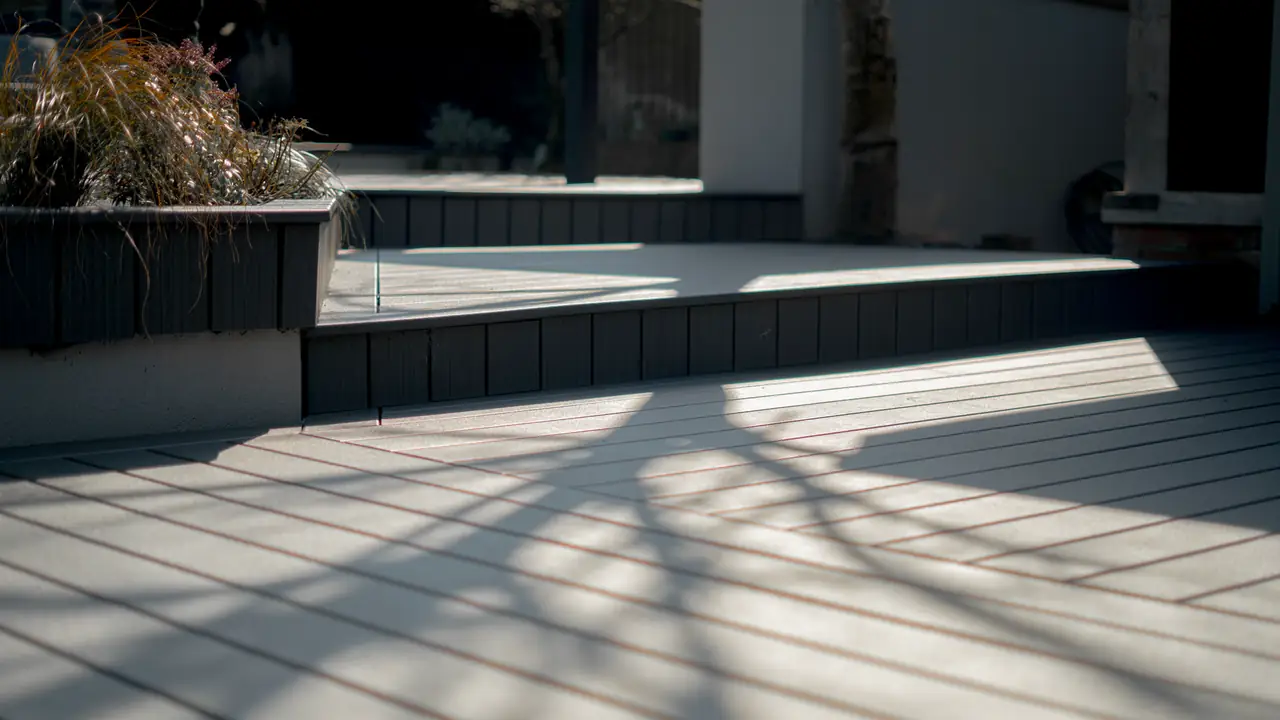 Deck steps and a raised planter, with tree shadows across the boards