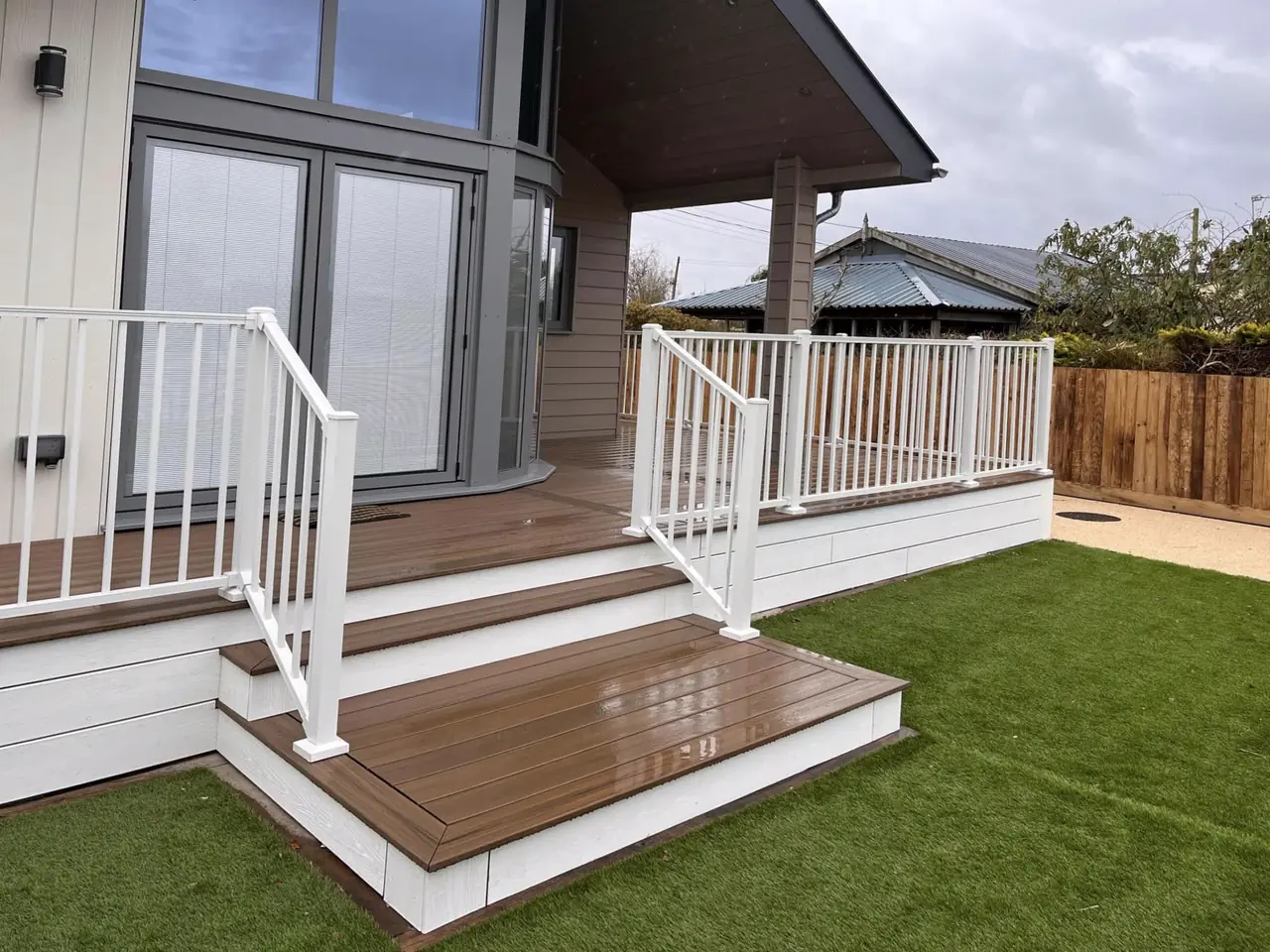 A Trex Enhance deck in Toasted Sand with steps at a holiday lodge, white Trex Signature railing and white fascia