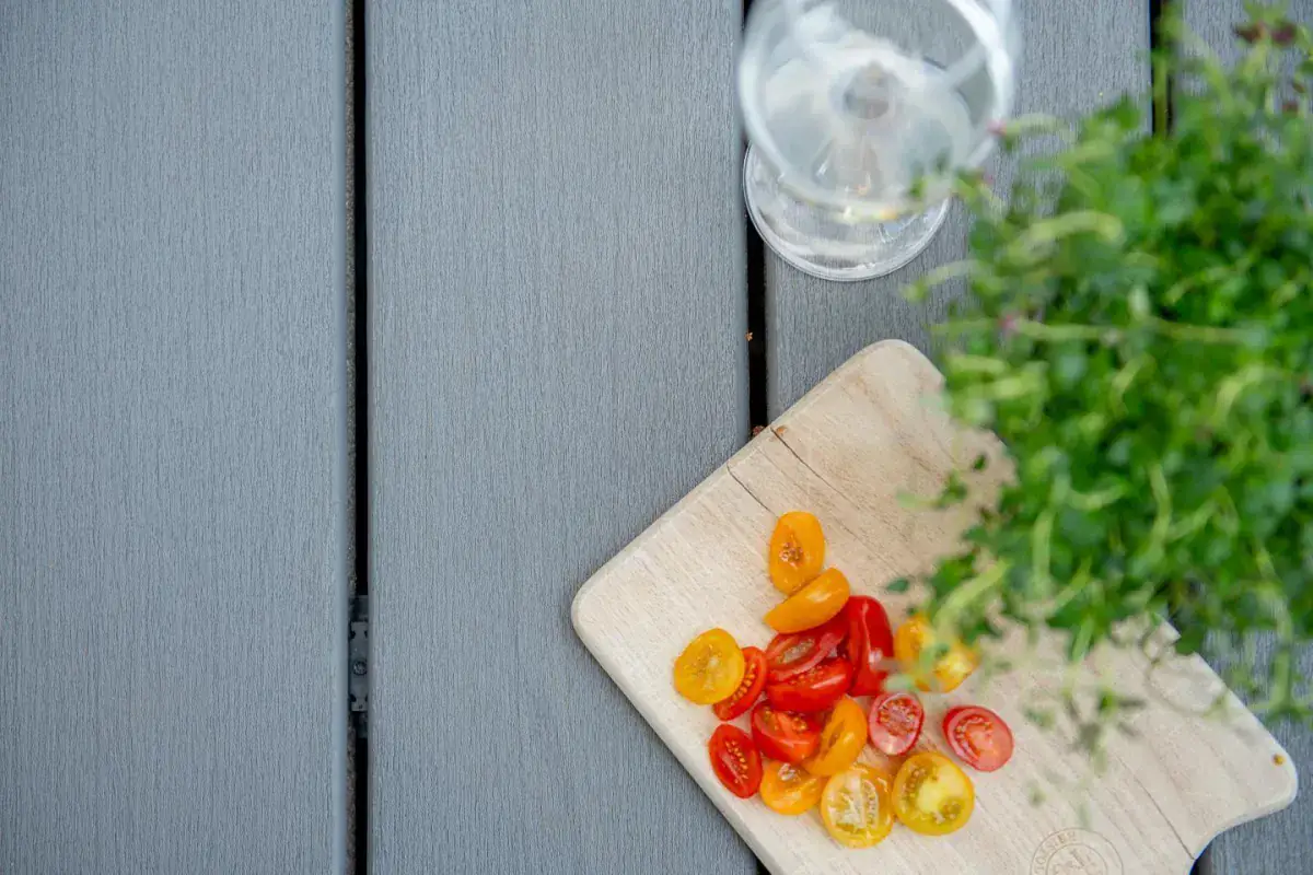 Close-up of grey deck boards with a chopping board and fresh herbs
