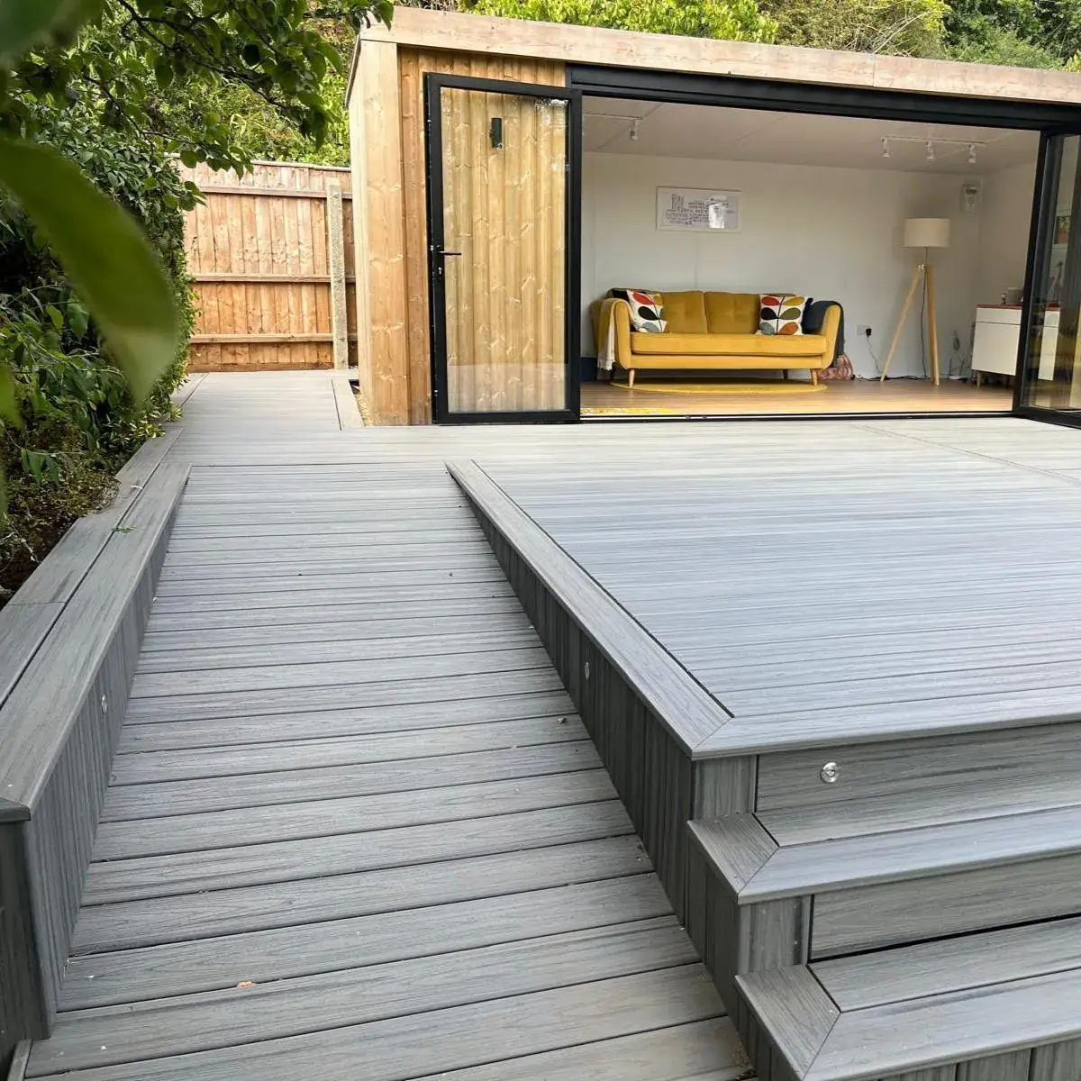 Grey Trex decking with a ramp and steps leading to a garden room
