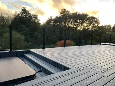 A Trex Transcend deck in Island Mist at sunset, with steps down to a hot tub and lights set into the steps