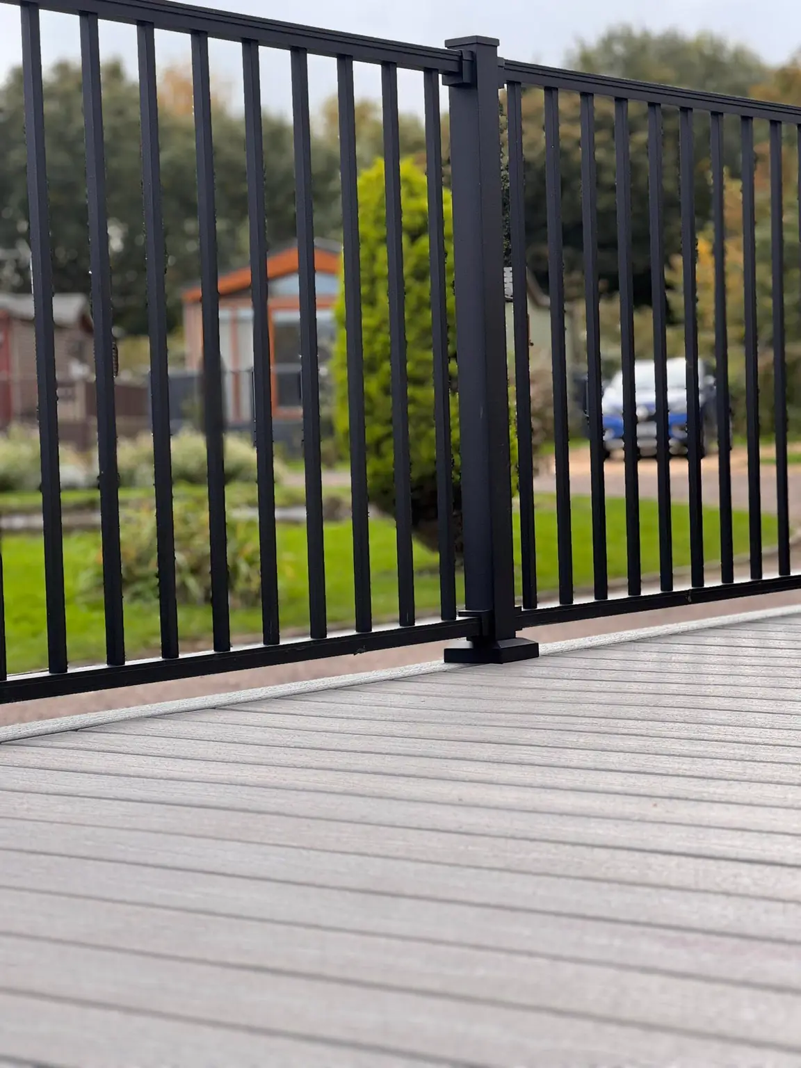 Close-up of a black railing post and balusters on a grey deck