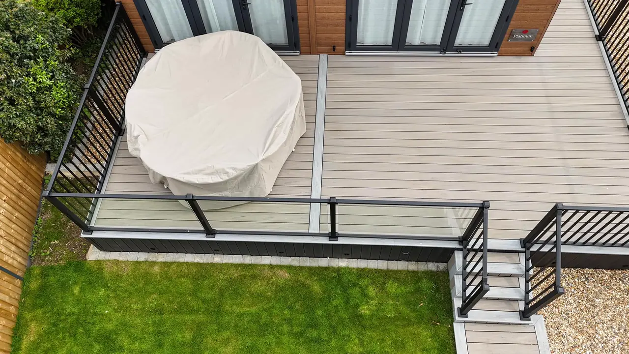 Looking down on a grey deck with black railing and steps to the lawn