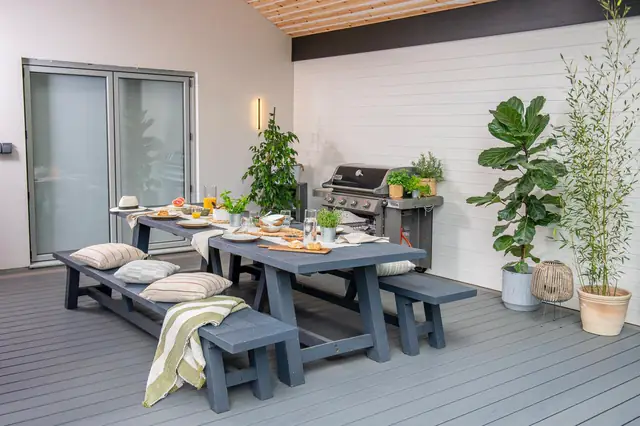 A covered dining area on a grey Trex Transcend deck, outdoor kitchen behind