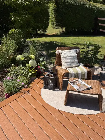 A lounge chair on a round rug on a warm brown Trex Signature deck