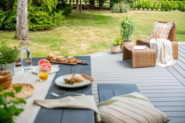 Lunch laid out on a long table on a grey Trex Transcend deck beside the lawn
