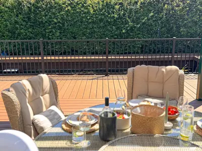 A raised Trex Signature terrace with black railing and garden chairs
